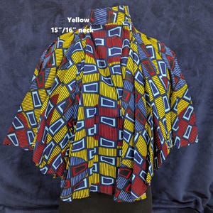 Puede incluir: Una blusa estampada vibrante con cuello de 38/41 cm, con un dise&ntilde;o geom&eacute;trico en amarillo, azul y rojo. La tela tiene un patr&oacute;n repetitivo de rect&aacute;ngulos y l&iacute;neas. La palabra "Yellow" est&aacute; impresa en la parte superior.