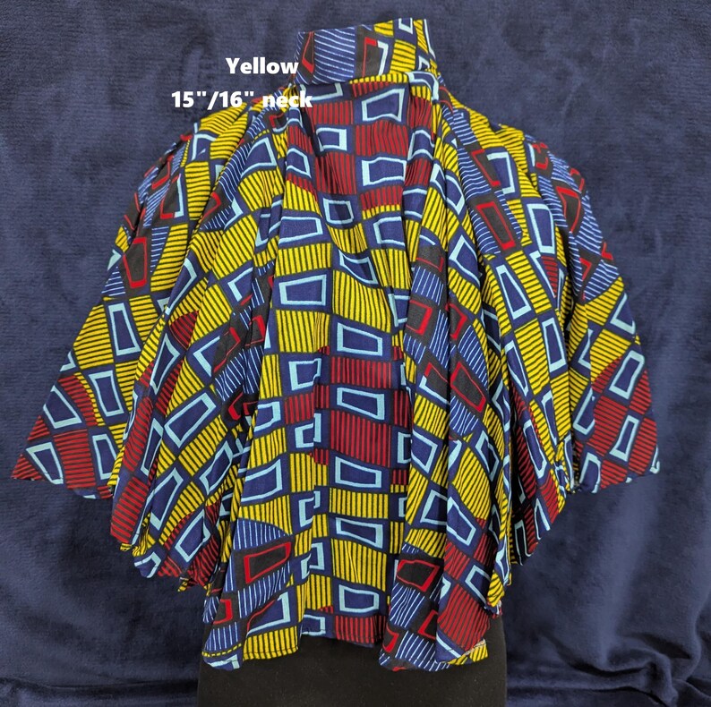 Puede incluir: Una blusa estampada vibrante con cuello de 38/41 cm, con un dise&ntilde;o geom&eacute;trico en amarillo, azul y rojo. La tela tiene un patr&oacute;n repetitivo de rect&aacute;ngulos y l&iacute;neas. La palabra "Yellow" est&aacute; impresa en la parte superior.
