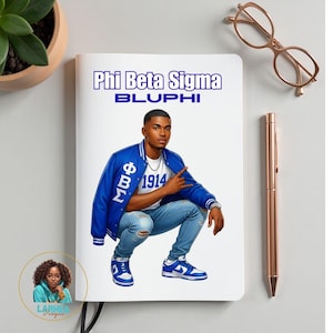 May include: A white notebook featuring a graphic of a person wearing a blue jacket and jeans. The text "Phi Beta Sigma BLUPHI" is printed at the top. A rose gold pen and glasses are next to the notebook.