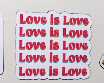May include: A white sticker with the phrase "Love is Love" repeated five times in red, with orange and yellow accents. The sticker has a rounded rectangular shape and is likely a decorative item.