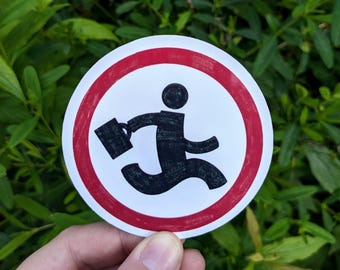 May include: A round sticker featuring a black silhouette of a person running with a briefcase inside a red-bordered white circle. The sticker is held against a backdrop of green foliage.