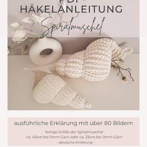 Op de afbeelding: Twee crèmekleurige, gehaakte spiraalvormige schelpen. De afbeelding bevat de tekst "PDF-HÄKELANLEITUNG Spiralmuschel" en "ausführliche Erklärung mit über 80 Bildern". De afmeting is ongeveer 43 cm met 5 mm garen of 23 cm met 3 mm garen.