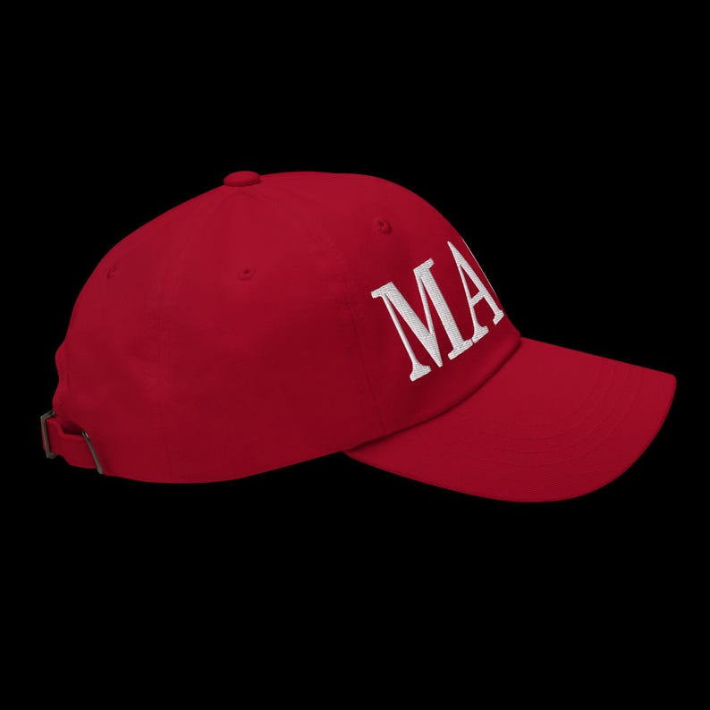 Op de afbeelding: Rode baseballcap met de wit geborduurde letters "MA" op de voorkant. De pet heeft een gebogen klep en een verstelbare band aan de achterkant. De hoed is gemaakt van een zacht materiaal.