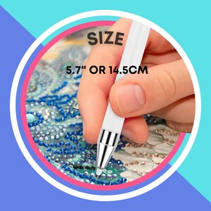 May include: Close-up of a white diamond painting pen with a silver tip. The pen is 5.7" or 14.5 cm long. The pen is being used to place a diamond on a diamond painting canvas.