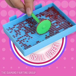 May include: A blue plastic tray with a grid pattern holds small red round beads. A green plastic tool with a round edge is rolling over the beads. The text "DRILL WHEEL" is written in white letters on a pink and purple background.