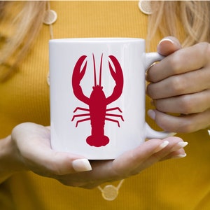 K&ouml;nnte beinhalten: Wei&szlig;e Keramiktasse mit einem roten Hummer-Silhouetten-Design.