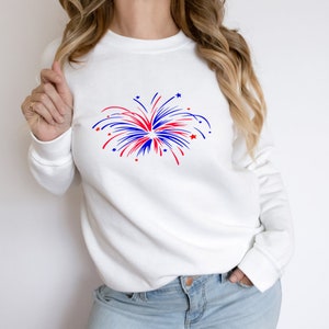 May include: White sweatshirt with a red, white, and blue firework graphic.