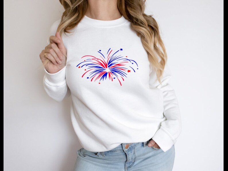 May include: White sweatshirt with a red, white, and blue firework graphic.