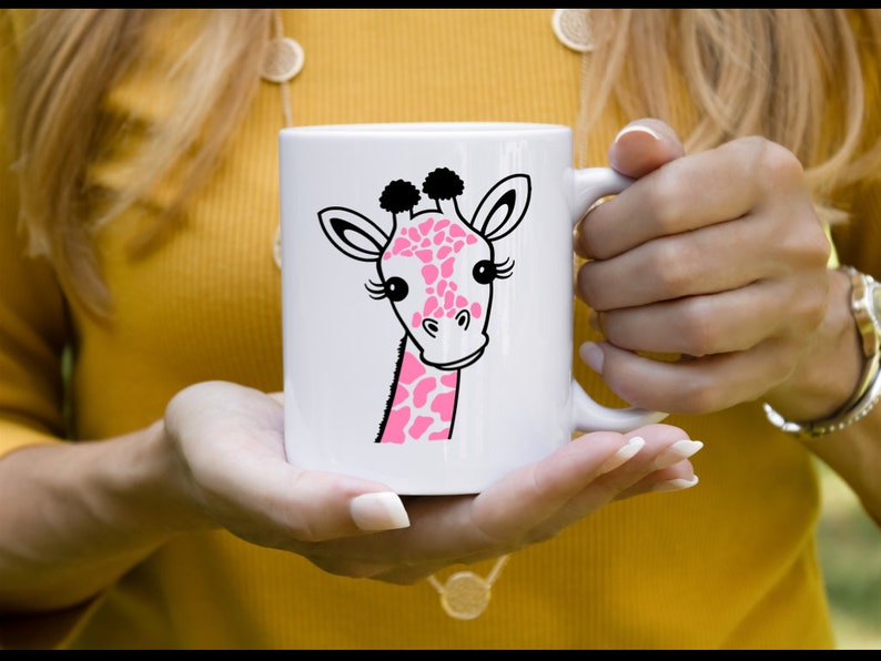 Puede incluir: Taza de cer&aacute;mica blanca con una ilustraci&oacute;n de jirafa de dibujos animados rosa y negra. La jirafa tiene pesta&ntilde;as y una nariz rosa.