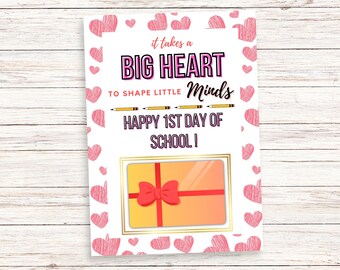 May include: A white card with pink hearts and the text "It takes a BIG HEART to SHAPE LITTLE Minds HAPPY 1ST DAY OF SCHOOL!"  A gift card is shown in the center of the card.