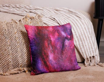 May include: A square throw pillow featuring a vibrant galaxy print with deep shades of magenta, purple, and black, accented by scattered white star-like specks across the entire surface of the fabric, creating a celestial nebula effect.