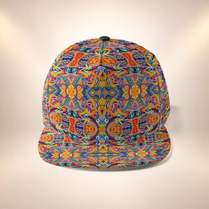Puede incluir: Una gorra de béisbol con un patrón vibrante, simétrico e intrincado en tonos naranja, amarillo, azul, rosa y morado. El diseño cubre toda la corona y la visera plana, con un pequeño botón negro en el centro de la parte superior de la gorra.