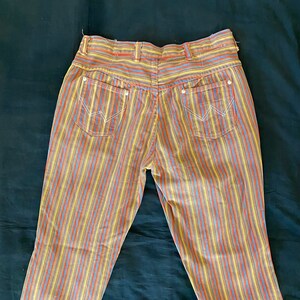 K&ouml;nnte beinhalten: Eine gestreifte Hose in Gelb, Orange, Blau und Rot. Die Hose hat eine hohe Taille und eine gerade Bein.