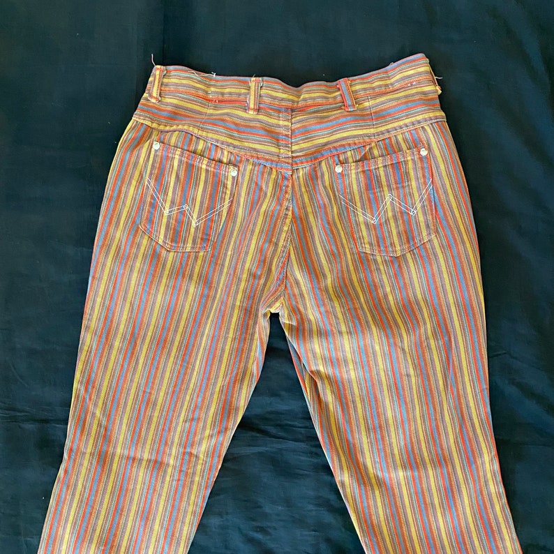 K&ouml;nnte beinhalten: Eine gestreifte Hose in Gelb, Orange, Blau und Rot. Die Hose hat eine hohe Taille und eine gerade Bein.