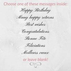 May include: A white card with a gray watercolor background. The card has a list of birthday greetings in black cursive writing: Happy Birthday, Many happy returns, Best wishes, Congratulations, Bonne F&ecirc;te, F&eacute;liciations, Meilleurs voeux. The card also has the text "or leave blank!" in pink cursive writing.