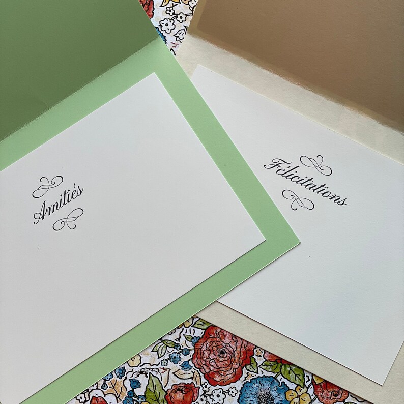 May include: Two blank greeting cards with green and beige envelopes. The card on the left has the word "Amiti&eacute;s" in cursive script. The card on the right has the word "Felicitations" in cursive script.