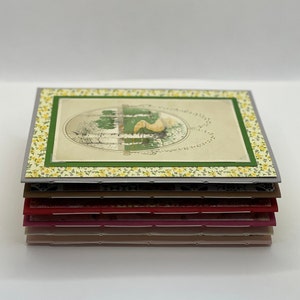 Puede incluir: Una pila de tarjetas hechas a mano con un dise&ntilde;o floral y una ilustraci&oacute;n vintage de un p&aacute;jaro en un jard&iacute;n. Las tarjetas est&aacute;n superpuestas en tonos de gris, marr&oacute;n, rojo, rosa y beige.