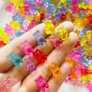 May include: Assortment of colorful gummy bear charms in various shades of pink, blue, yellow, orange, and red. The gummy bears are translucent and have a shiny finish.