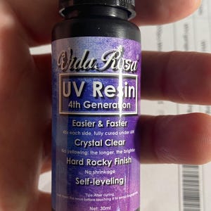 May include: A black bottle of Vida Rosa UV Resin. The label features the text "UV Resin" and "4th Generation". Additional text includes "Easier & Faster", "Crystal Clear", "Hard Rocky Finish", and "Self-leveling". The bottle contains 30ml of resin.