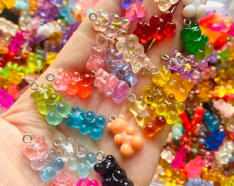 Op de afbeelding: Assortiment van kleurrijke gummy bear bedels met zilveren springringen. De bedels zijn gemaakt van helder, doorschijnend plastic en zijn verkrijgbaar in verschillende kleuren, waaronder rood, oranje, geel, groen, blauw, paars, roze en wit. De bedels zijn perfect om een ​​leuke en speelse touch toe te voegen aan sieraden, sleutelhangers en andere knutselprojecten.