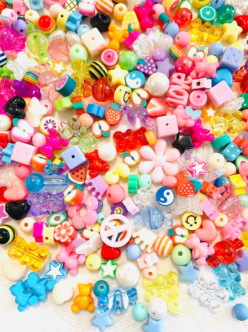 May include: A large assortment of colorful plastic beads in various shapes, including stars, hearts, flowers, fruits, and animals. The beads are perfect for making jewelry, crafts, and other projects.