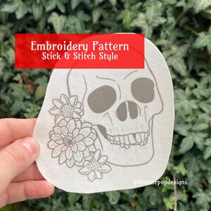 May include: Embroidery pattern for a skull with flowers, in a stick and stitch style. The pattern is printed on white fabric.