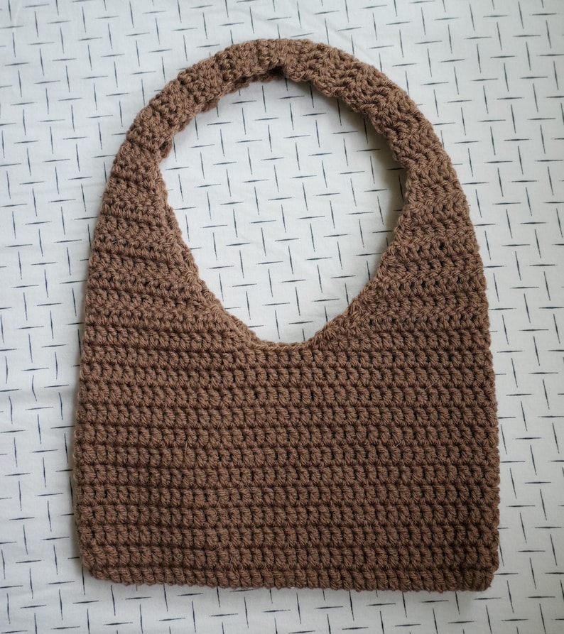 May include: A brown crocheted tote bag with a single strap.
