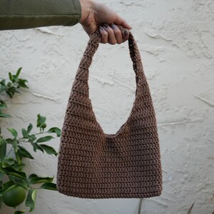 May include: A brown crocheted shoulder bag with a single strap.