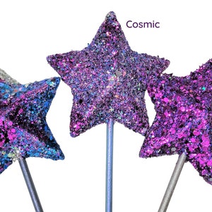 May include: Three glitter star wands with different color combinations: Galaxy, Cosmic, and Purple Rain. The wands are made of a silver metal stick with a star-shaped topper.