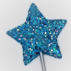 May include: A blue glitter star-shaped topper on a silver stick. The star is covered in iridescent glitter.