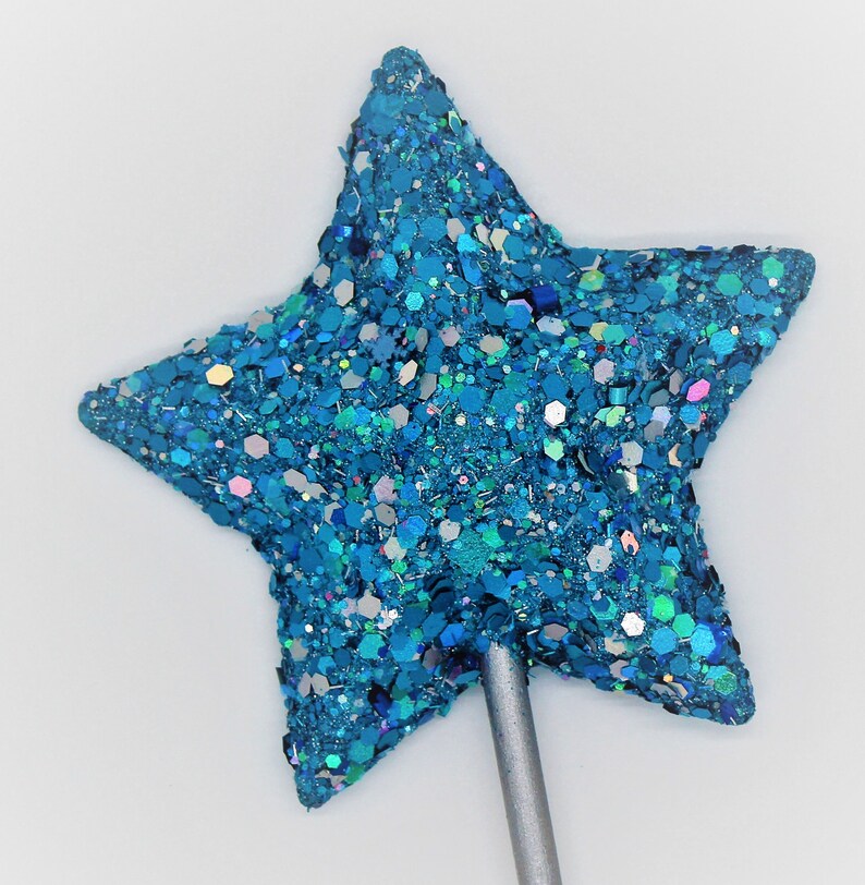May include: A blue glitter star-shaped topper on a silver stick. The star is covered in iridescent glitter.