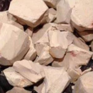 May include: A close-up of a pile of light brown, irregularly shaped clay chunks.