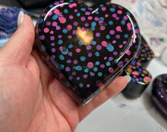 Heart-shaped paperweight dotted with blue, pink, teal and purple hues on black