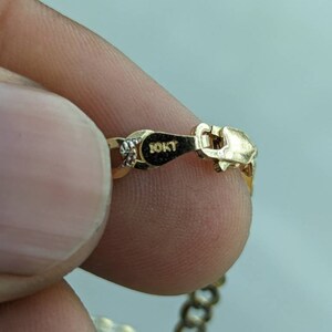 Pode incluir: Um colar de corrente de ouro com um fecho que diz "10KT".