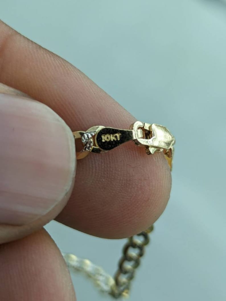 Pode incluir: Um colar de corrente de ouro com um fecho que diz "10KT".