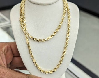 May include: A gold rope chain necklace displayed on a white mannequin. The chain is thick and has a shiny finish.