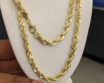 May include: A gold rope chain necklace. The chain is thick and has a twisted design. The necklace is displayed on a white stand.