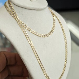 Pode incluir: Um colar de corrente de ouro com um design de corte de diamante. A corrente est&aacute; em um expositor branco.