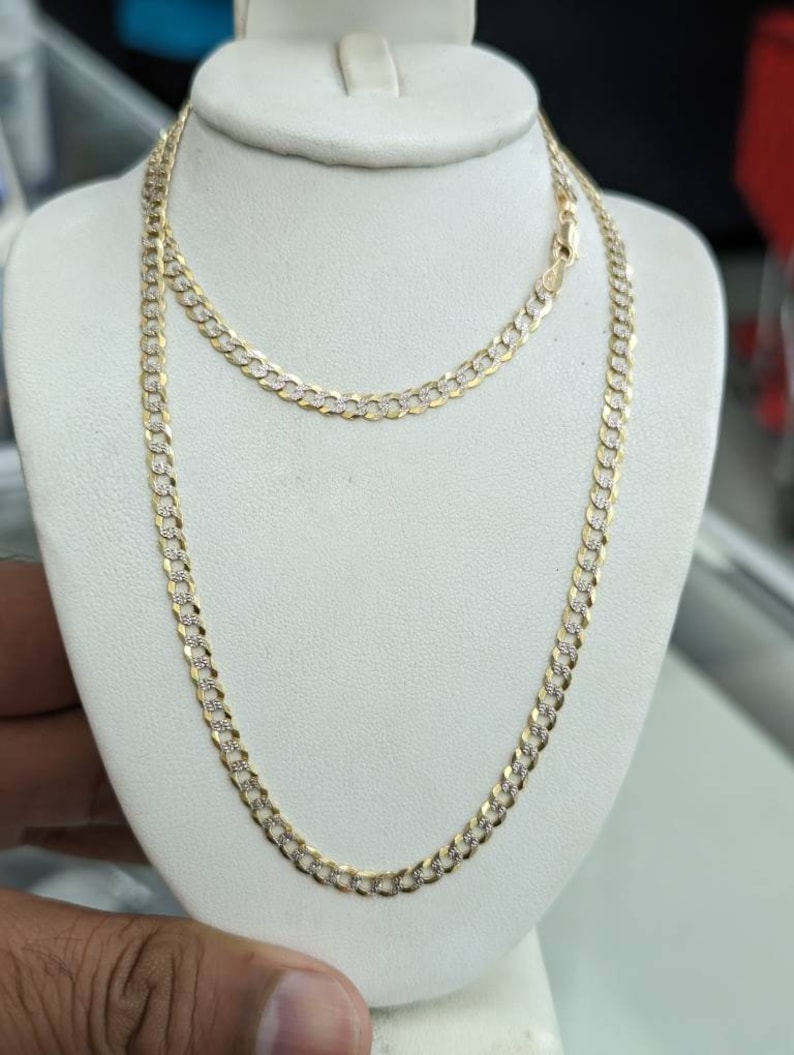 Pode incluir: Um colar de corrente de ouro com um design de corte de diamante. A corrente &eacute; exibida em um manequim branco.