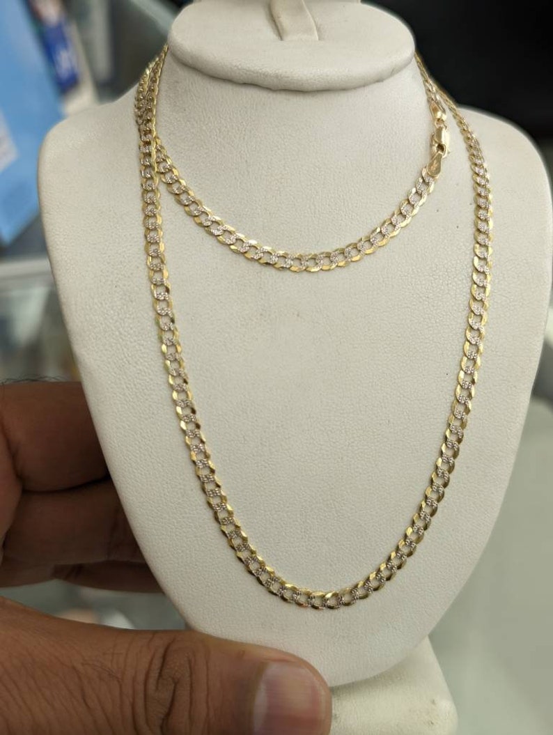 Pode incluir: Um colar de corrente de ouro com um design de corte de diamante. A corrente est&aacute; em um expositor branco.