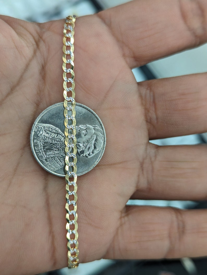 May include: A gold and silver curb chain necklace is displayed next to a coin. The chain has alternating gold and silver links. The necklace is approximately 0.1 inches wide.