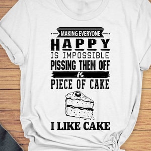 May include: White unisex t-shirt with black text that reads "Making everyone happy is impossible pissing them off is piece of cake I like cake". The text is surrounded by a black dashed line. A black and white illustration of a piece of cake is below the text.