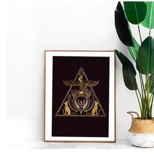 Könnte beinhalten: Ein gerahmter Druck mit schwarzem Hintergrund und goldenem Design. Das Design zeigt ein Dreieck mit einer geflügelten Katze im Inneren, einer geflügelten Figur über der Katze und zwei Katzen auf beiden Seiten des Dreiecks.