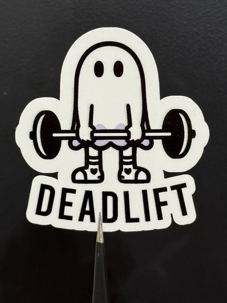 Pu&ograve; includere: Un adesivo bianco con un fantasma dei cartoni animati che solleva un bilanciere. Il fantasma ha due occhi neri e indossa calzini a righe e scarpe con cuori. La parola "DEADLIFT" &egrave; stampata in grassetto, in lettere nere.