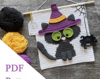 May include: A crocheted Halloween wall hanging featuring a black cat wearing a purple witch hat with a yellow band. The cat has green eyes and a pink nose. A black spider hangs from a web. The words "PDF Pattern" are visible.