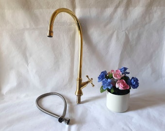 May include: A gold-colored faucet with a curved spout and a single handle. The faucet is attached to a white counter and has a flexible hose.