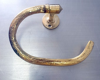 May include: A gold-toned towel ring with an ornate design. The ring is made of metal and has a smooth, polished finish.