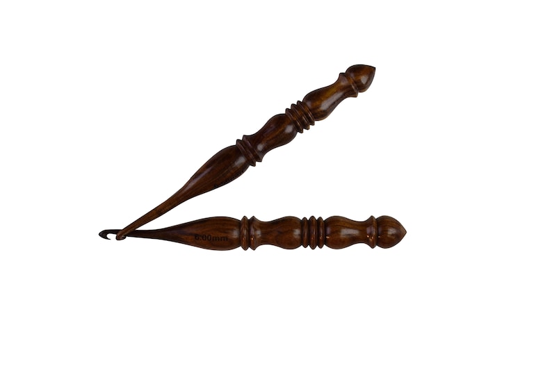 May include: Two wooden crochet hooks, one with a 10.00mm size marking. The hooks are brown with a dark wood grain and have a pointed tip.