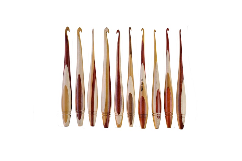 May include: Set of ten wooden crochet hooks with a natural wood and red wood finish. The hooks are all different sizes and are arranged in a row.