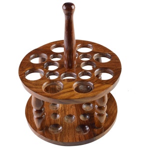 May include: A wooden stand with a central post and two tiers of circular holes, designed to hold a collection of items like paintbrushes or tools.